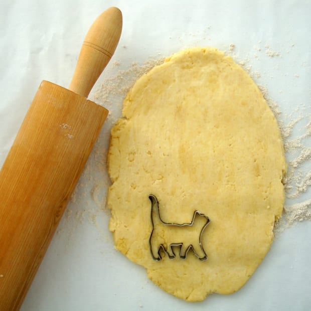Cat shaped cookie cutter sitting on dough with rolling pin