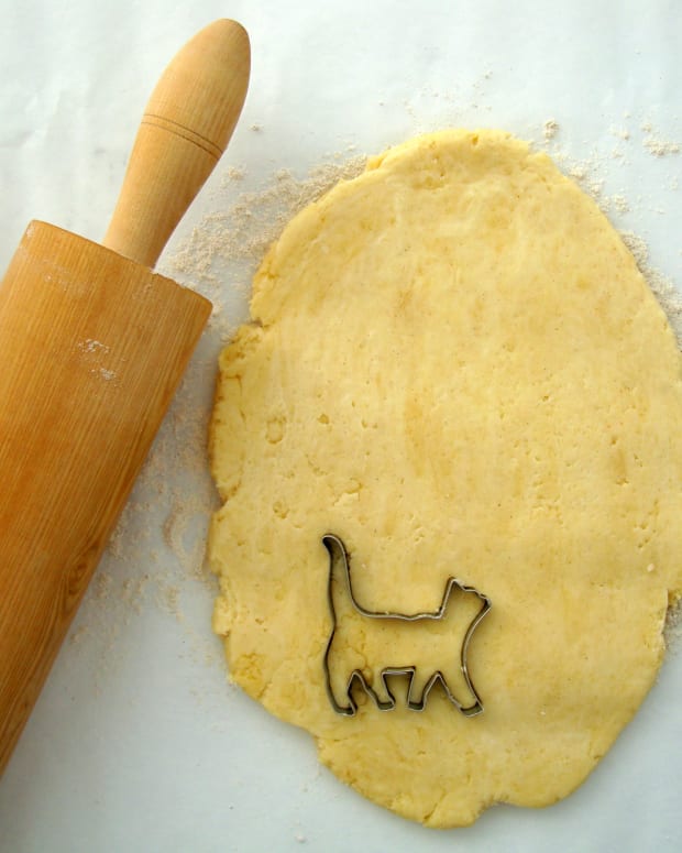 Cat shaped cookie cutter sitting on dough with rolling pin